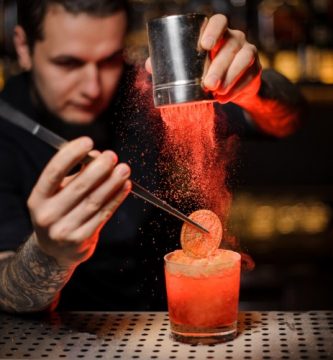 Mixólogo decorando un cóctel con técnicas de mixología