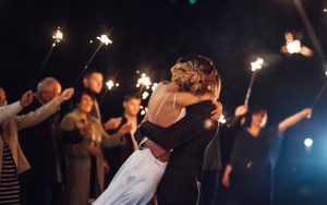 Pareja abrazándose en una fiesta postboda en Madrid con invitados y bengalas