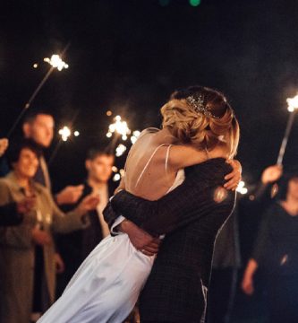 Pareja abrazándose en una fiesta postboda en Madrid con invitados y bengalas