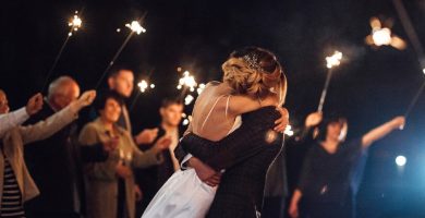 Pareja abrazándose en una fiesta postboda en Madrid con invitados y bengalas