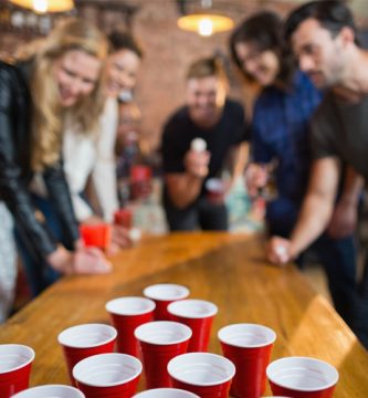 Grupo de amigos jugando al beer pong como uno de los juegos para fiestas más populares