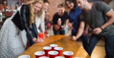 Grupo de amigos jugando al beer pong como uno de los juegos para fiestas más populares