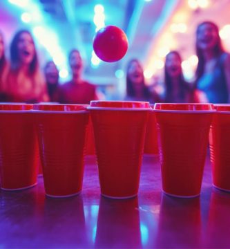 Beer Pong, uno de los juegos de beber para fiestas, con vasos rojos y una pelota en juego