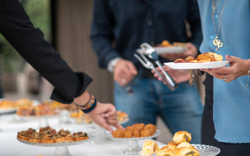 Invitados sirviéndose aperitivos de un buffet con comida para fiestas y picoteo